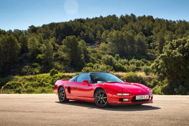 A red Honda NSX is parked in front of a green forest under clear blue sky, 2K Desktop Wallpaper