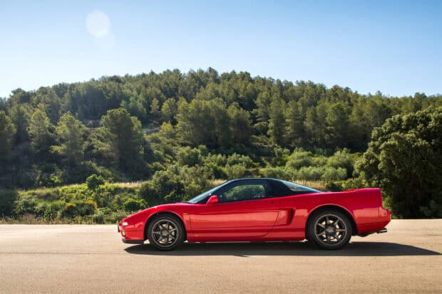 A red Honda NSX sports car is parked on a sunny road with a forest background, 2K Desktop Wallpaper