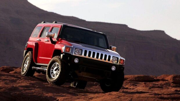 A red Hummer H3 driving over rough desert terrain with rocky hills in the background, HD Desktop Wallpaper