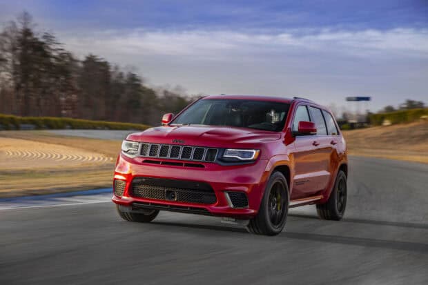 A red Jeep Grand Cherokee drives on a racetrack with trees and sky in the background, 2K Desktop Wallpaper