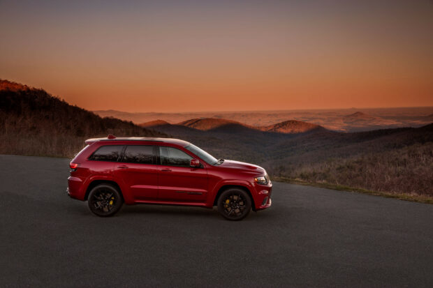 A red Jeep Grand Cherokee is parked on a mountain road during sunset with a scenic view, 2K Desktop Wallpaper