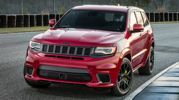 A red Jeep Grand Cherokee is parked on a race track next to tire barriers, HD Desktop Wallpaper