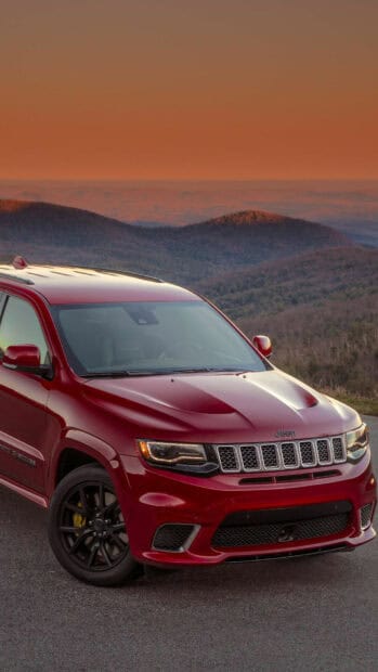 A red Jeep Grand Cherokee is parked on a mountain road with scenic hills under a warm sunset, HD Mobile Wallpaper