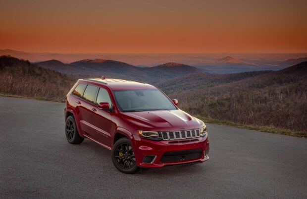 A red Jeep Grand Cherokee is parked on a mountain road at sunset showing the scenic landscape, 2K Desktop Wallpaper
