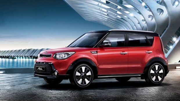 A red Kia Soul car is parked near waterfront with futuristic building in the background, HD Desktop Wallpaper