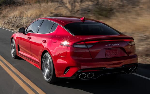 A red Kia Stinger driving fast on a desert highway under sunlight, HD Desktop Wallpaper