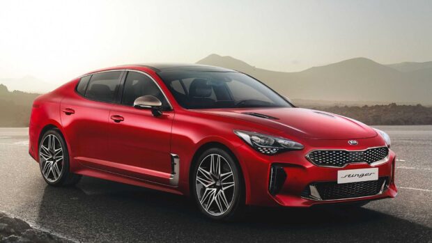 A red Kia Stinger is parked on a paved road with mountains in the background, HD Desktop Wallpaper