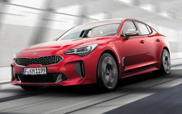 A red Kia Stinger is driving fast on a modern road capturing its sporty design, HD Desktop Wallpaper