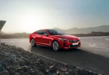 A red Kia Stinger is parked on an open road with rocky terrain and mountains in the background, HD Desktop Wallpaper