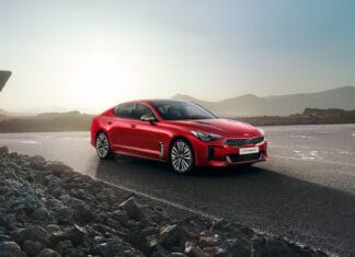 A red Kia Stinger is parked on an open road with rocky terrain and mountains in the background, HD Desktop Wallpaper