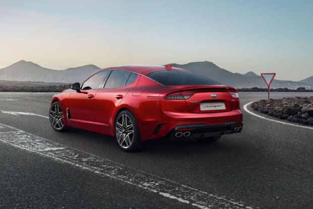 A red Kia Stinger is parked on a curved mountain road under a clear sky, 2K Desktop Wallpaper