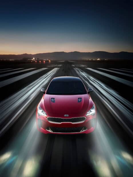 A red Kia Stinger driving fast on a runway with mountains in the background at dusk, HD Mobile Wallpaper
