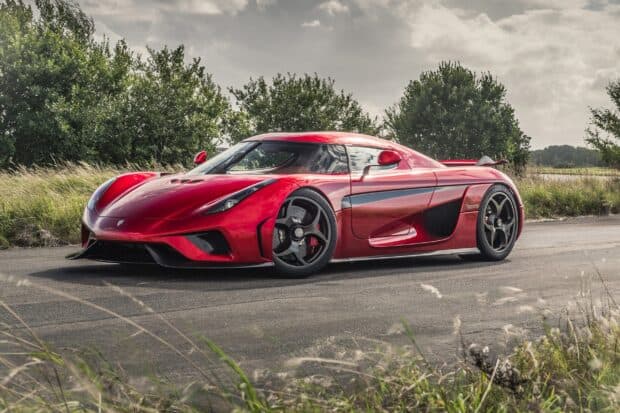 A red Koenigsegg is parked on a countryside road surrounded by grass and trees, 2K Desktop Wallpaper