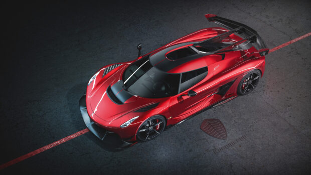 A red Koenigsegg sports car is parked on a textured surface with branding, 4K Desktop Wallpaper
