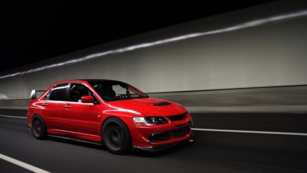 A red Lancer Evo speeding through a dimly lit tunnel showcasing its aerodynamic design, HD Desktop Wallpaper