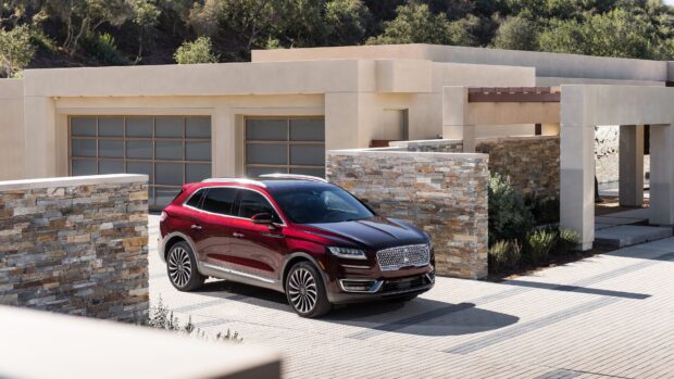 A red Lincoln SUV is parked in front of a modern house with stone walls and large windows, 4K Desktop Wallpaper