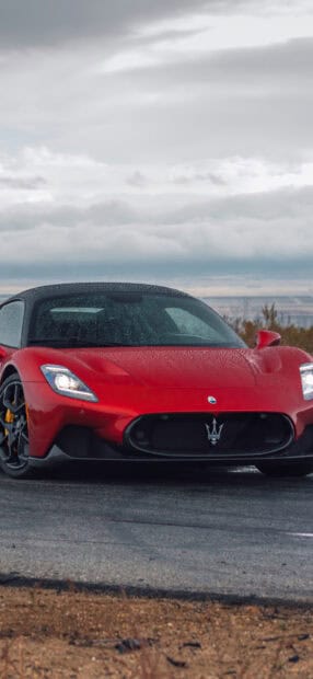 A red Maserati Mc20 is parked on a wet road under cloudy skies, showcasing its sleek design, HD Phone Wallpaper