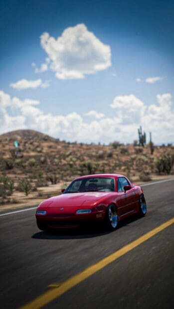 A red Mazda MX 5 Miata is driving on a desert road under a bright blue sky with clouds, HD Mobile Wallpaper