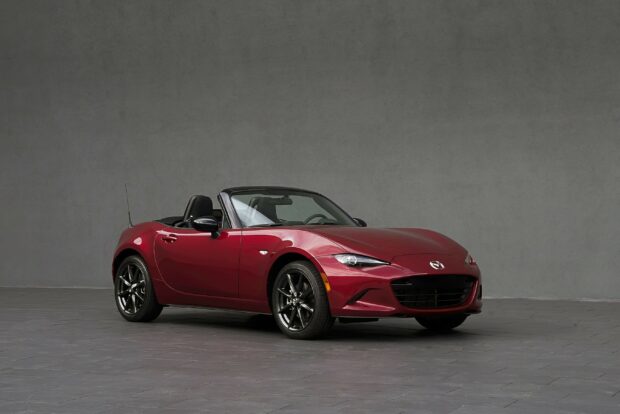 A red Mazda MX 5 Miata is parked on a tiled floor with a gray wall background, 2K Desktop Wallpaper