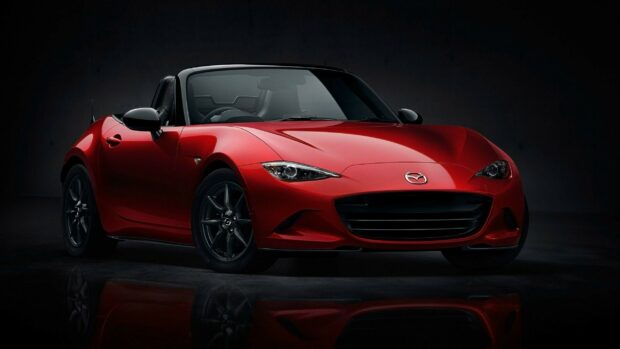 A red Mazda MX 5 Miata sports car is shown from the front on a dark reflective floor, 2K Desktop Wallpaper