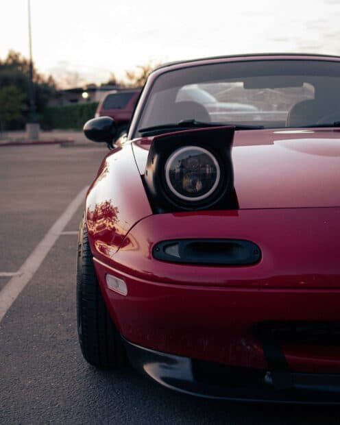 A red Mazda MX 5 Miata with a single raised pop up headlight parked in an outdoor lot during sunset, HD Desktop Wallpaper