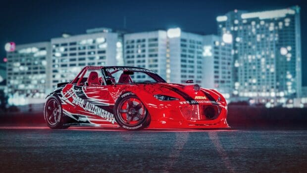 A red Mazda MX 5 Miata with racing decals is parked on a city street at night, HD Desktop Wallpaper