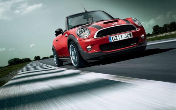 A red Mini Cooper accelerating on a curved race track with a driver inside, HD Desktop Wallpaper