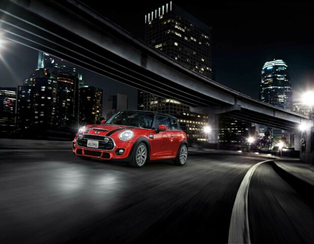 A red Mini Cooper drives on a curved road under city lights at night, HD Desktop Wallpaper