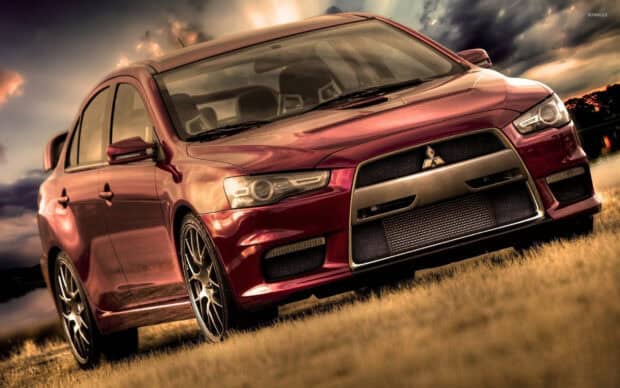 A red Mitsubishi Lancer Evo is parked on grass under a dramatic cloudy sky, HD Desktop Wallpaper