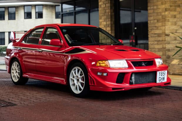 A red Mitsubishi Lancer Evo with white wheels parked on a paved urban street, HD Desktop Wallpaper