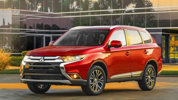 A red Mitsubishi Outlander is parked in front of a glass office building at sunset, 4K Desktop Wallpaper