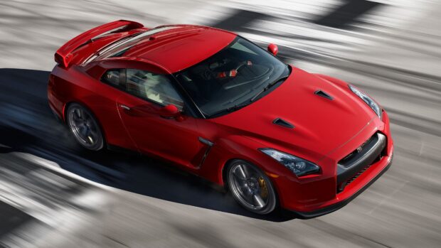 A red Nissan GT R is speeding around the corner on a race track in this action shot, 4K Desktop Wallpaper