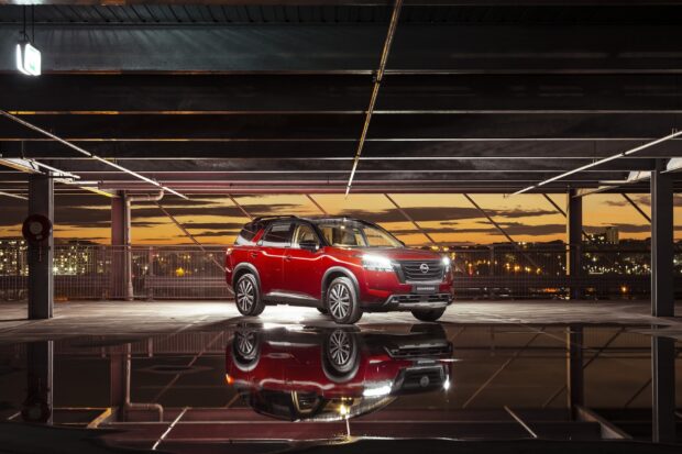 A red Nissan Pathfinder is parked in an urban parking garage at sunset with reflections on the wet floor, HD Desktop Wallpaper