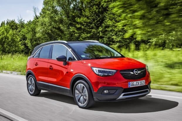 A red Opel Crossland drives smoothly along a green roadside in this Opel Crossland wallpapers image, HD Desktop Wallpaper