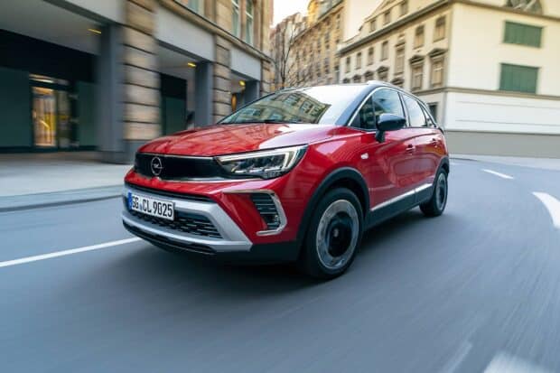 A red Opel Crossland is driving fast through an urban area with buildings in the background, HD Desktop Wallpaper
