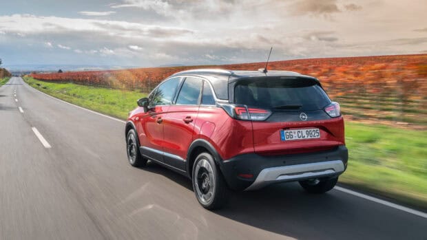 A red Opel Crossland is driving along a country road with autumn scenery in the background, 4K Desktop Wallpaper