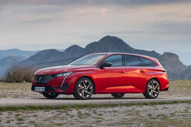 A red Peugeot 308 is parked in front of rocky mountains under a cloudy sky, 2K Desktop Wallpaper