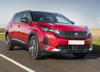 A red Peugeot 5008 drives on a clear road with fields in the background, 2K Desktop Wallpaper