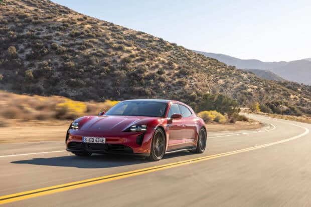 A red Porsche Taycan drives along a winding mountain road during daytime, 2K Desktop Wallpaper