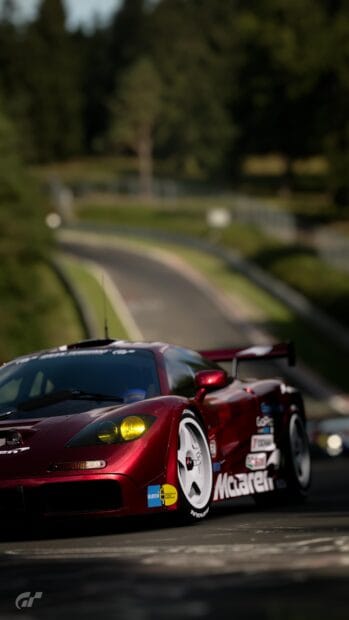 A red racing car speeds along a curvy track surrounded by trees in a racing game, 4K Phone Wallpaper