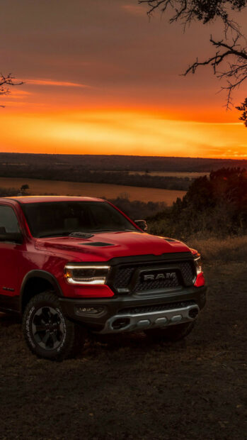 A red Ram pickup truck parked on a grassy hill during a vibrant sunset, HD Phone Wallpaper
