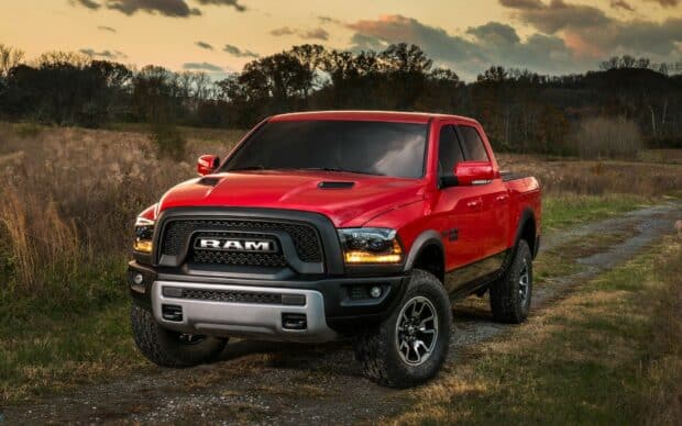 A red Ram truck stands on a rural dirt road with a scenic background of trees and cloudy sky, HD Desktop Wallpaper