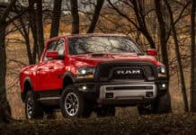 A red Ram truck is parked among tall trees in a forest during autumn, 4K Desktop Wallpaper