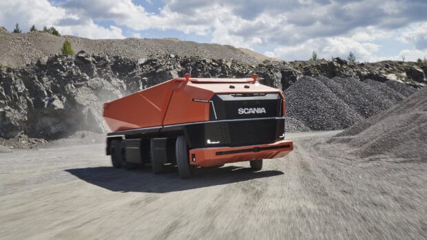 A red Scania truck is driving through a rocky landscape with piles of gravel, 2K Desktop Wallpaper
