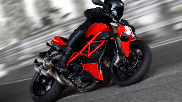 A rider on a red street bike leans into a sharp turn on a track, 4K Desktop Wallpaper