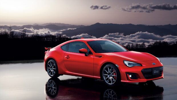 A red Subaru BRZ car is parked with a mountain range and cloudy sky in the background, 4K Desktop Wallpaper