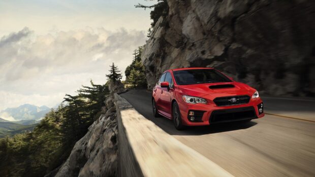 A red Subaru WRX speeds along a winding mountain road with trees and cliffs nearby, HD Desktop Wallpaper