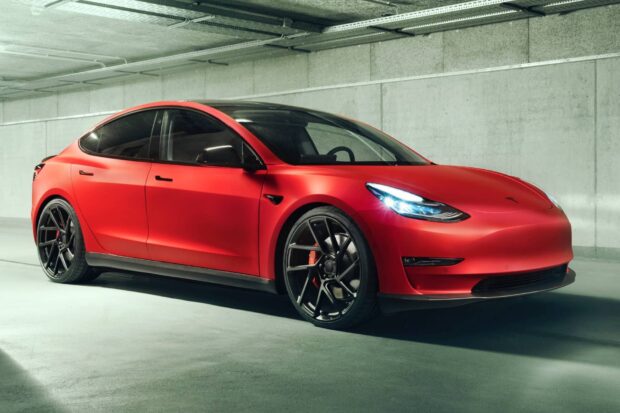 A red Tesla Model 3 is parked in an indoor garage with lights on, HD Desktop Wallpaper