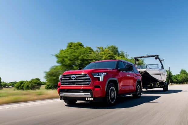 A red Toyota Sequoia is towing a boat down the highway on a clear sunny day, HD Desktop Wallpaper