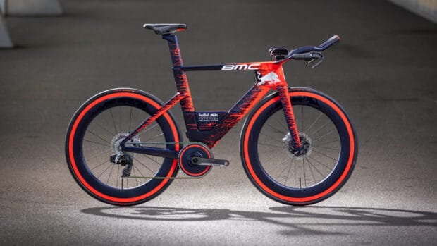 A red and black Bmc bike with aerodynamic design is displayed on a gray surface, HD Desktop Wallpaper